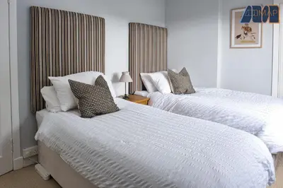 a bedroom with two beds with white sheets at Paisley Haven on Renfrew Road in Merksworth