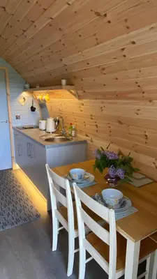 a kitchen with a wooden table with chairs and a sink at The Fells - Campsie Luxury Pods with hot tub in Glasgow