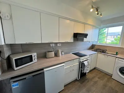 a kitchen with white cabinets and a sink and a microwave at Seaside Apartment in Helensburgh
