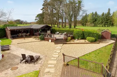 a garden with a pavilion with chairs and a deck at Brig o Doon 2 in Ayr