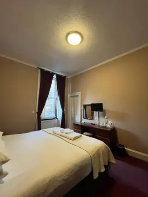 a bedroom with a large white bed and a window at Edinburgh Whisky House Hotel in Edinburgh
