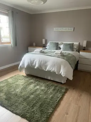 a bedroom with a large bed with a green rug at Fraoch, Pets welcome in Port Bannatyne