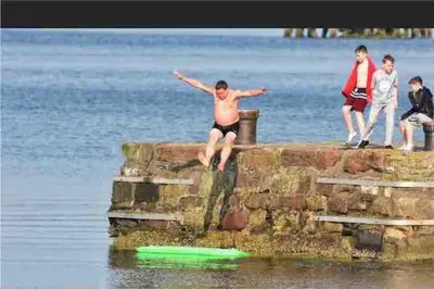 a man jumping off of a pier in the water at Fraoch, Pets welcome in Port Bannatyne