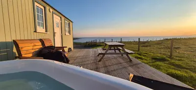 a person sitting on a bench next to a hot tub at North Muasdale Farm, Ewe View in Muasdale