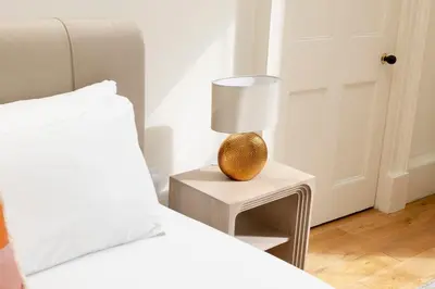 a bedroom with a bed and a lamp on a table at JOIVY Exclusive house with free parking in Edinburgh