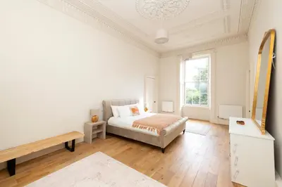 a white bedroom with a bed and a mirror at JOIVY Exclusive house with free parking in Edinburgh