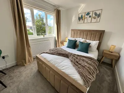 a bedroom with a large bed with blue pillows at Elite 3 bedroom family house with free parking in Newton Mearns