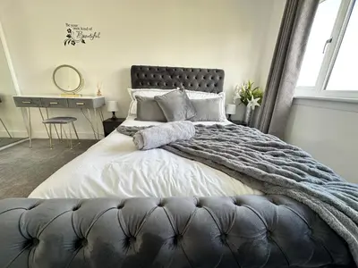 a bedroom with a large bed with a blanket at Elite 3 bedroom family house with free parking in Newton Mearns