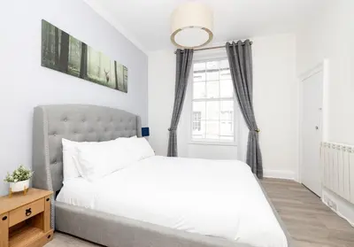 a bedroom with a white bed and a window at Argyl - Charming 2 Bedroom Apartment on Thistle Street in Edinburgh