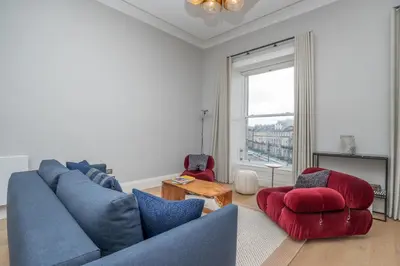 a living room with a blue couch and two chairs at Flat with Majestic views in West End Wonderland in Edinburgh