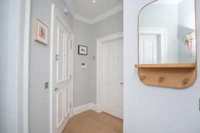 a hallway with white walls and a mirror at Flat with Majestic views in West End Wonderland in Edinburgh