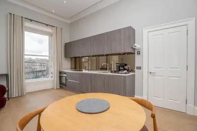 a kitchen with a wooden table in a room with a window at Flat with Majestic views in West End Wonderland in Edinburgh