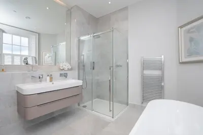 a white bathroom with a shower and a sink at Georgian Gem in the New Town in Edinburgh
