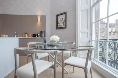 a dining room with a glass table and chairs at Georgian Gem in the New Town in Edinburgh