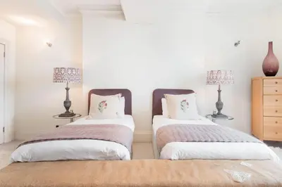 two beds in a room with white walls and two lamps at Super Central - Georgian Double Upper Flat with Castle Views in New Town in Edinburgh