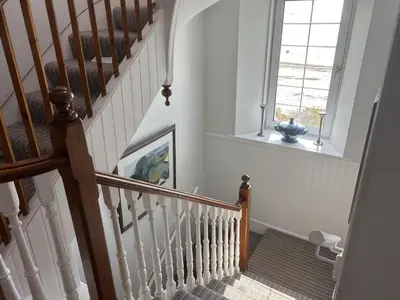 a hallway with a staircase with a window at Unique house in an idyllic situation on a beach in Port Ellen