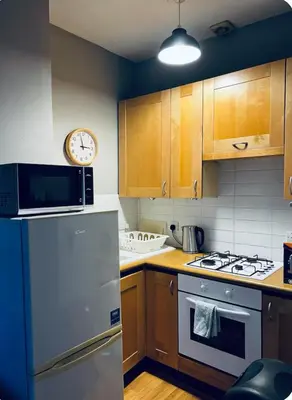 a kitchen with a refrigerator and a clock on the wall at Homely in Hampden in Glasgow
