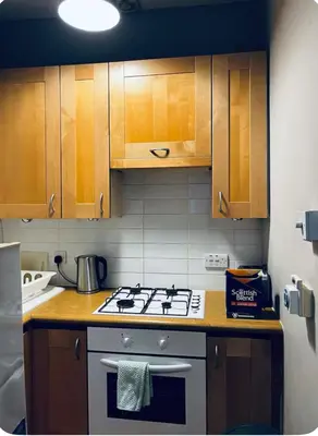 a kitchen with a stove and wooden cabinets at Homely in Hampden in Glasgow