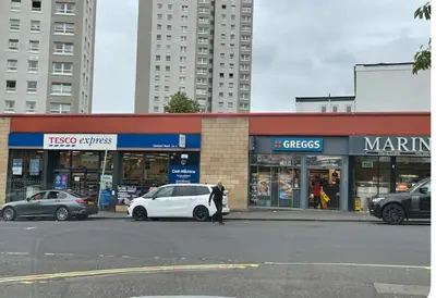 a man standing in front of a store with a white car at Homely in Hampden in Glasgow