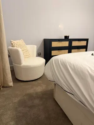 a bedroom with a bed and a white chair at Homely in Hampden in Glasgow
