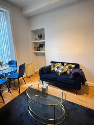 a living room with a blue couch and a glass table at Homely in Hampden in Glasgow