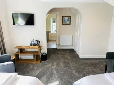 a room with two beds and a table and a television at Burnbank Bed and Breakfast in Moffat