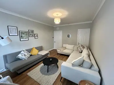 a living room with two couches and a table at West Dunbartonshire Flat, near Loch Lomond in Dumbarton