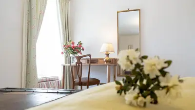 a room with a bed with a mirror and a vase of flowers at Beautiful House With Gardens Close To River Tay in Remony
