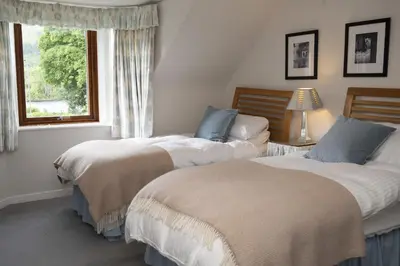 two beds in a room with a window at The Coach House in Saint Fillans
