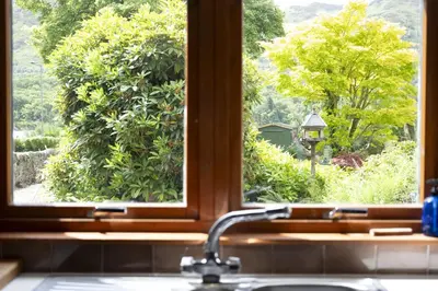 a kitchen sink with a window looking out at a garden at The Coach House in Saint Fillans