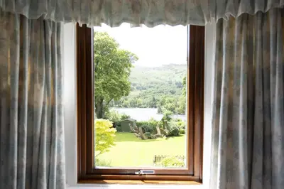 a window with a view of a green yard at The Coach House in Saint Fillans