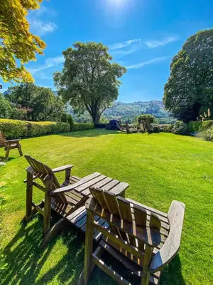 two wooden benches sitting in a grassy field at The Coach House in Saint Fillans