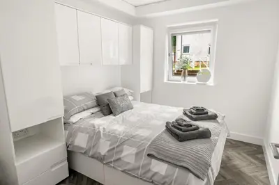 a white bedroom with a bed with towels on it at Beautiful 1 BR apt with private patio and free parking in Dunollie