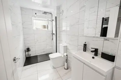 a white bathroom with a toilet and a sink at Beautiful 1 BR apt with private patio and free parking in Dunollie