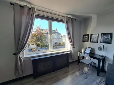 a room with a large window with a desk and a table at Glasgow Apartment close to the airport in Renfrew