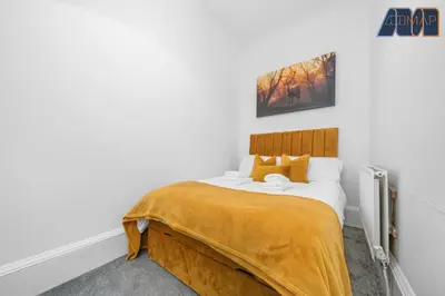 a bedroom with a bed with a yellow blanket on it at Albert Road in Gourock