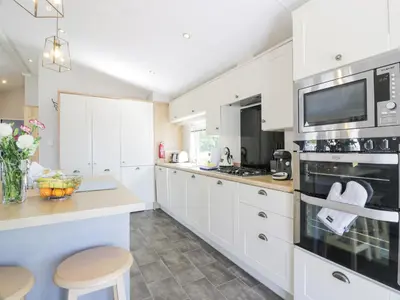 a kitchen with white cabinets and a tv at Bethany's Retreat in Wemyss Bay