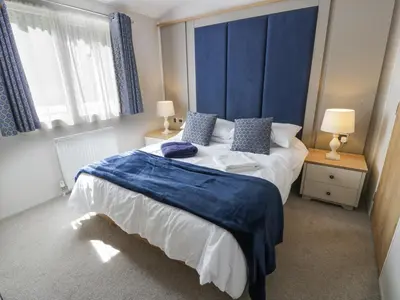 a bedroom with a large bed with blue pillows at Bethany's Retreat in Wemyss Bay