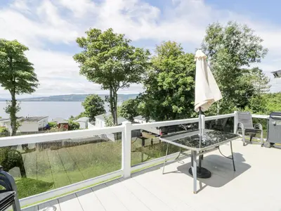 a balcony with a table and an umbrella at Olivia's Haven in Wemyss Bay
