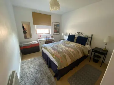 a bedroom with a bed and a table and a window at The Pentland Apartment in Penicuik