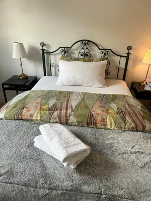a bed with a quilt and a towel on it at The Pentland Apartment in Penicuik