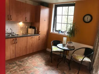 a kitchen with a table and chairs and a clock on the wall at The Pentland Apartment in Penicuik