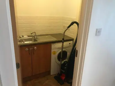 a bathroom with a vacuum cleaner next to a sink at The Pentland Apartment in Penicuik