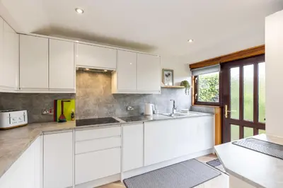 a kitchen with white cabinets and a window at 20 mins to Edinburgh 3 bedroom detached family house Wi-Fi Parking in Fife