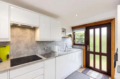 a kitchen with white cabinets and a window at 20 mins to Edinburgh 3 bedroom detached family house Wi-Fi Parking in Fife