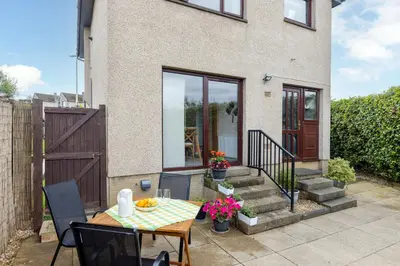 a patio with a table and chairs in front of a house at 20 mins to Edinburgh 3 bedroom detached family house Wi-Fi Parking in Fife