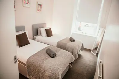 two beds in a small room with a window at 4 Beds - City Gateway Getaway with Free Parking in Glasgow