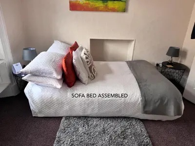 a bed with white sheets and red and white pillows at Heart of Oban in Oban