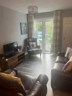 a living room with a couch and a television at Loch Lomond Riverside Apartments A in Balloch