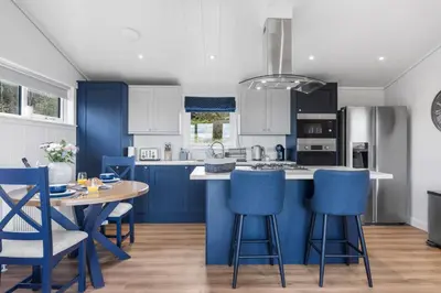 a kitchen with blue cabinets and a table and chairs at Arrochar View in Langbank
